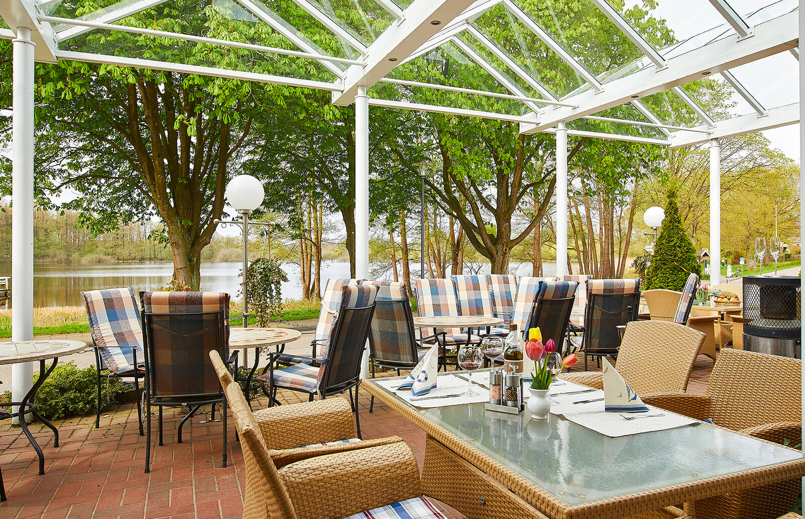 Überdachte Seeterrasse mit eingedeckten Tischen am Einfelder See